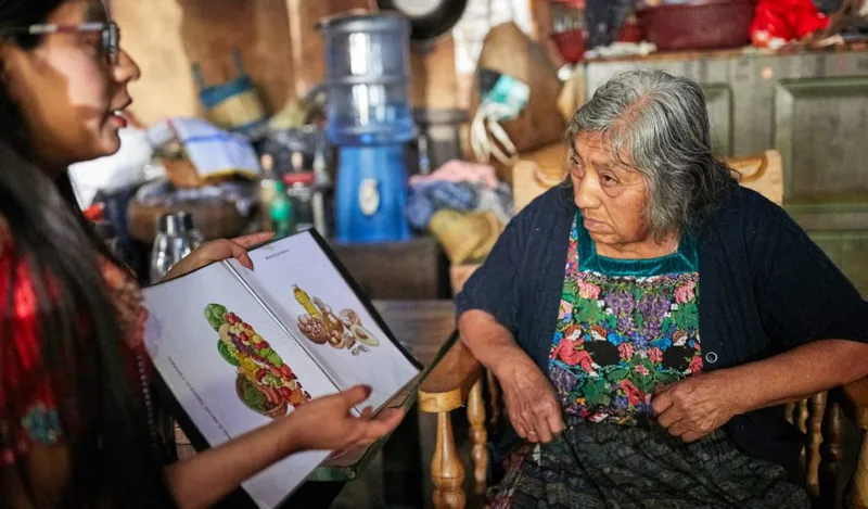 A Wuqu’ Kawoq health worker provides health education in a patient’s home.