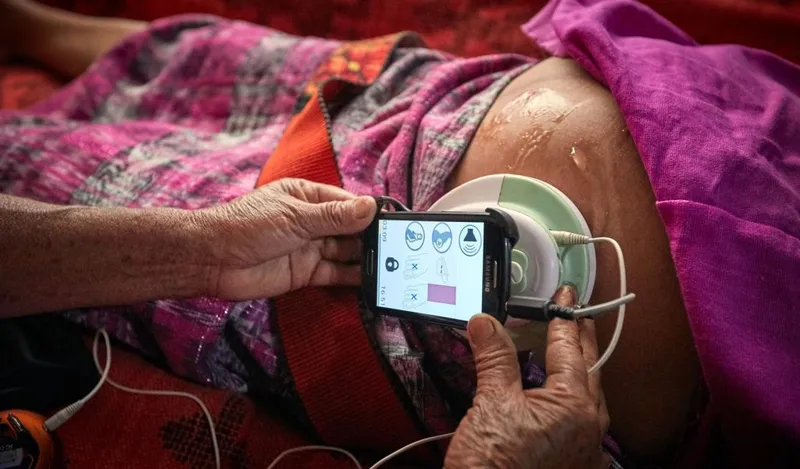 A traditional Maya midwife uses a smartphone during a prenatal visit.