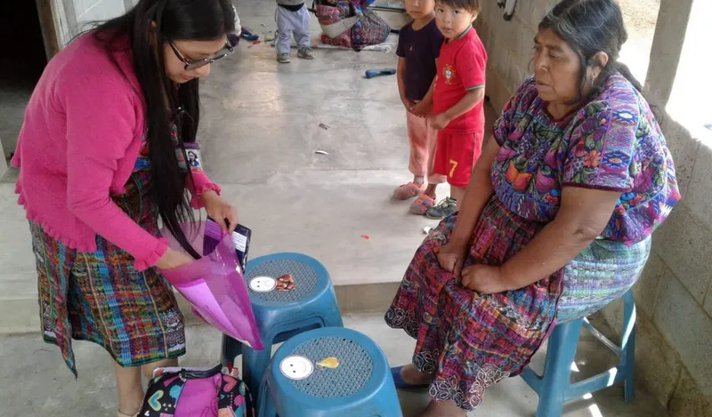A Wuqu’ Kawoq staff member uses portion-size teaching aids during a home diabetes education session.